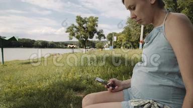 在公园使用手机的孕妇